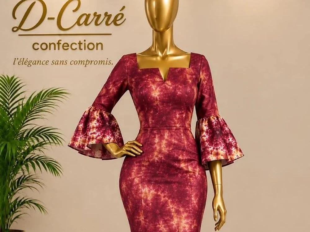 Robe sirène bordeaux à manches volantes, devant l'enseigne D-Carré Confection